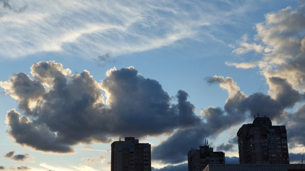 clouds in the sky above top of greyish buildings